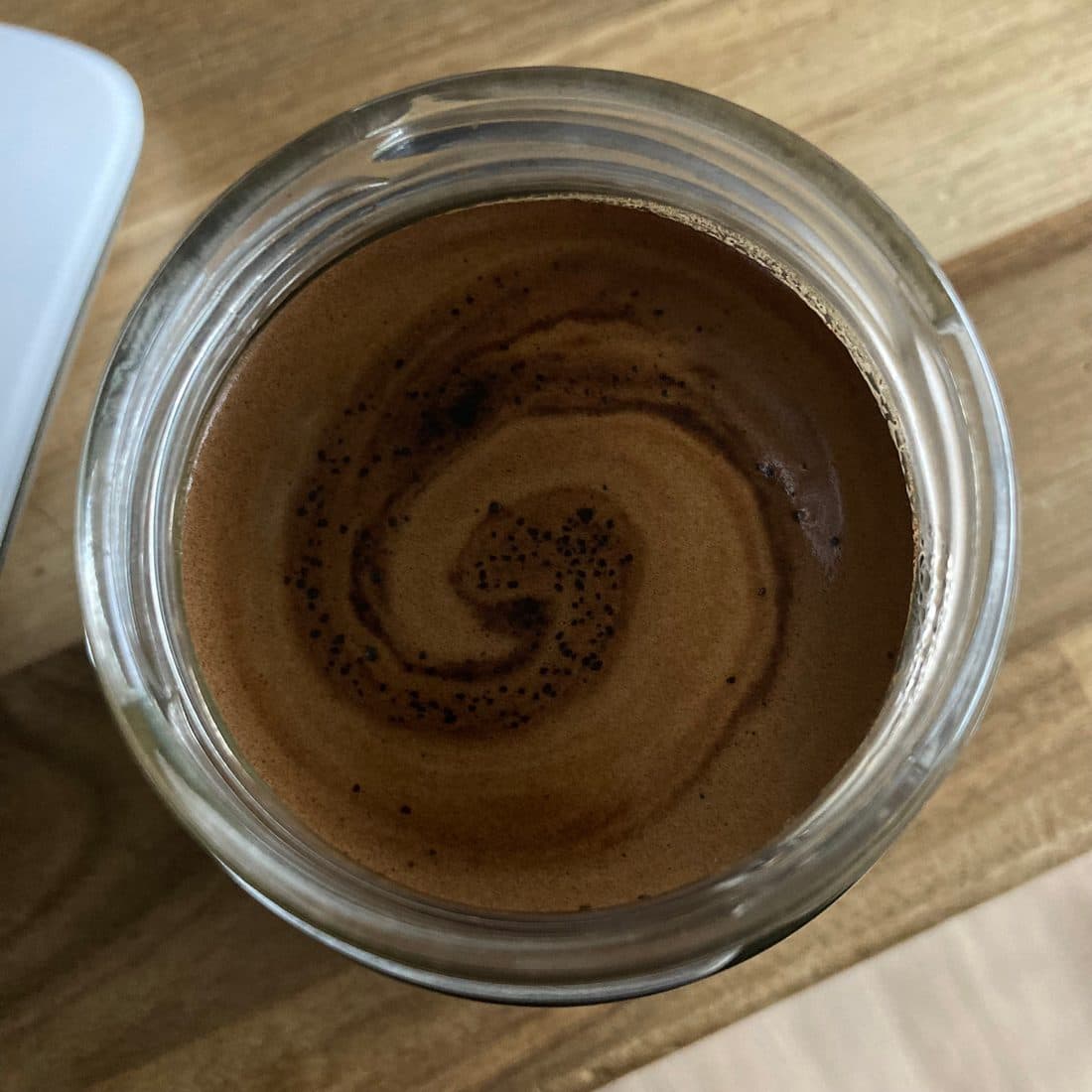 Von oben in ein Glas mit einem braunen Getränk geblickt, der Schaum bildet eine Spirale