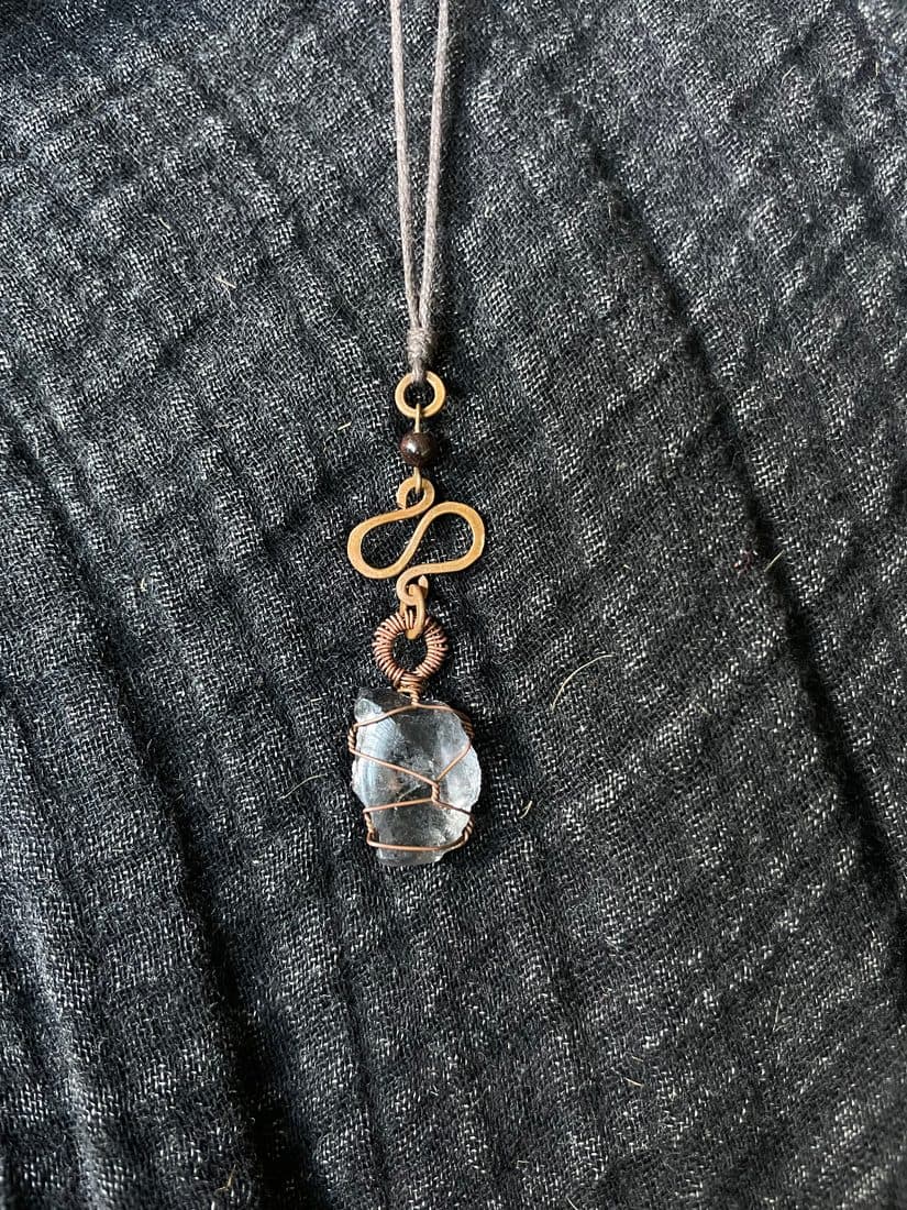Liegend auf dunklem Musselin, von der Seite: Ring, Granatperle, gehämmertes Element und die umwickelte Scherbe hintereinander