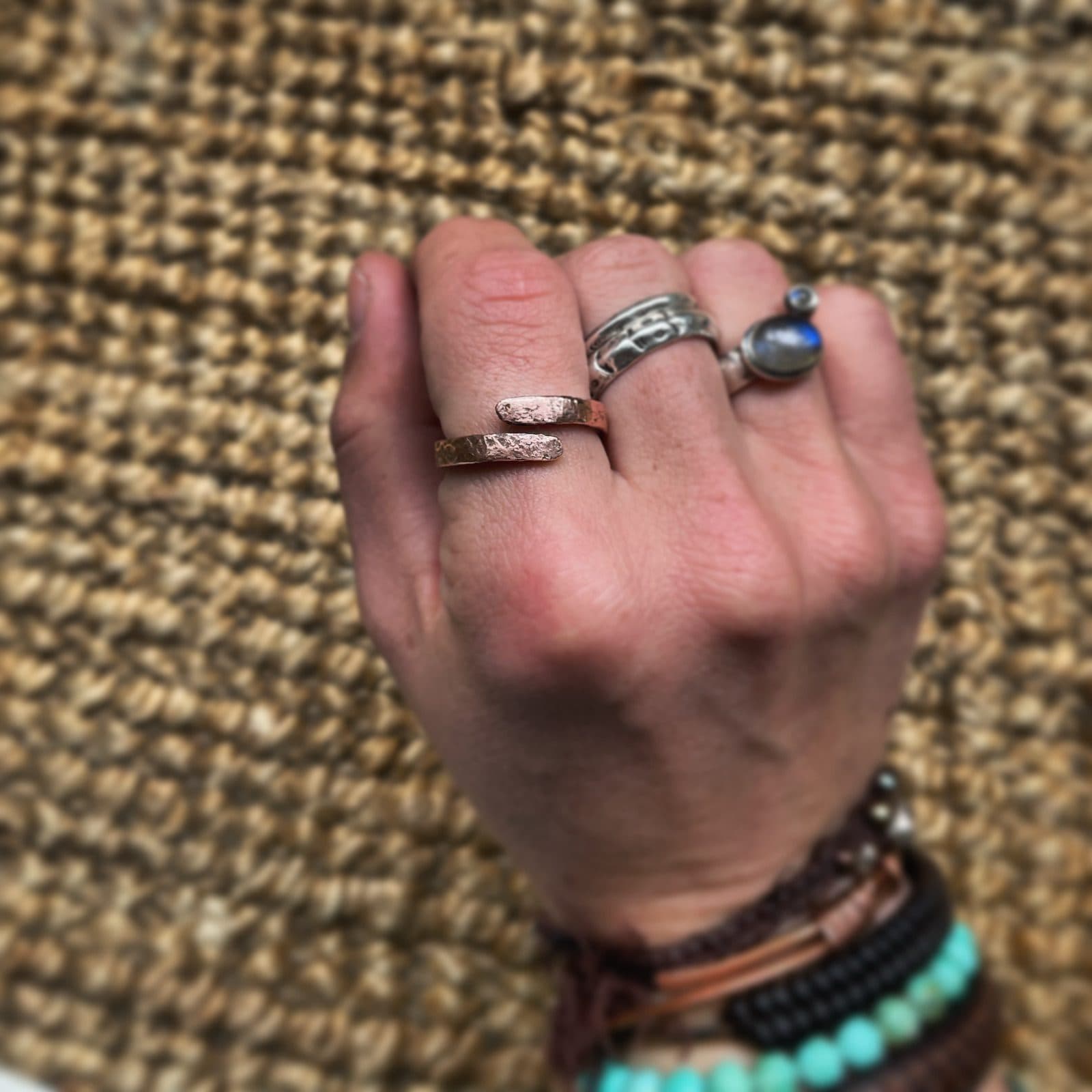 Offener, gehämmerter Kupferring am Finger, dessen beide abgerundete Enden sich nebeneinander vorbeischieben, ohne sich zu treffen